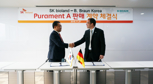 이근식 SK 바이오랜드 대표(왼쪽)가 27일 서울 테헤란로 비브라운 코리아에서 스테판 소이카 대표와 만나 SK 바이오랜드의 항균 골시멘트 Purament-A® 판매계약을 체결한 뒤 악수를 하고 있다. <SKC 제공>